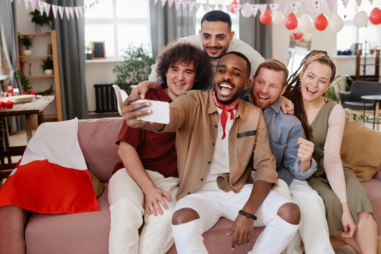 Diverse group of friends happily taking a selfie during a cozy home party.