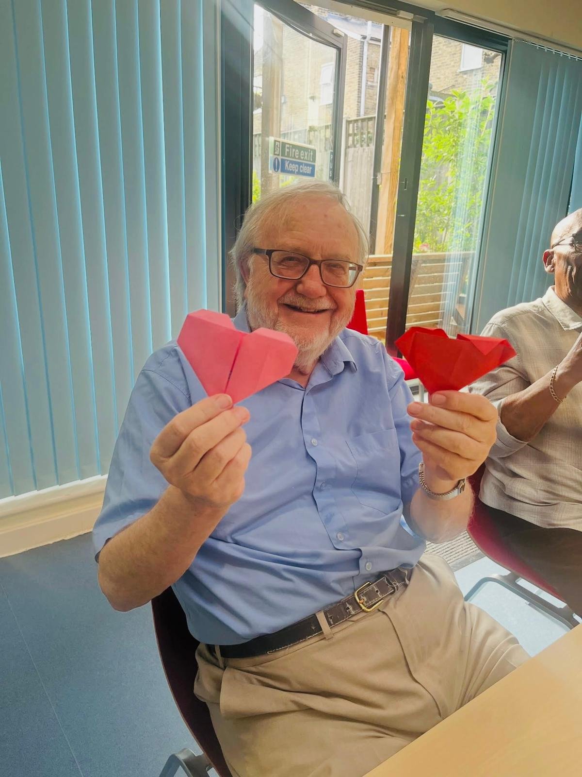 an old man holding origami heart